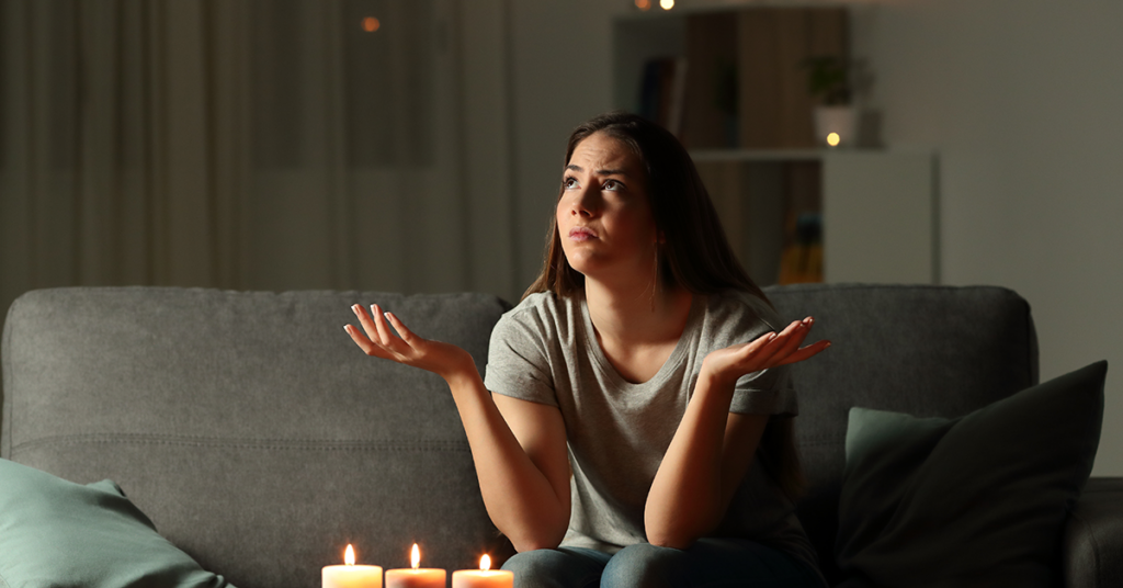 Woman with candles lit and her hands up with her shoulders shrugged