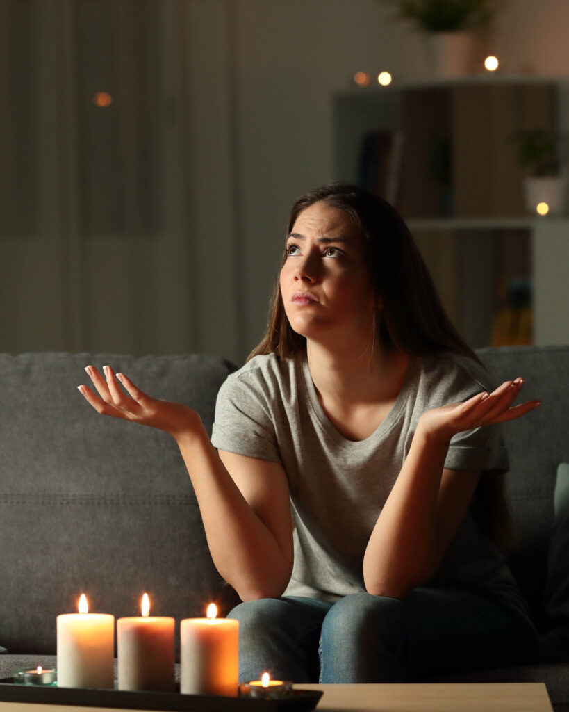 Woman with candles lit and her hands up with her shoulders shrugged