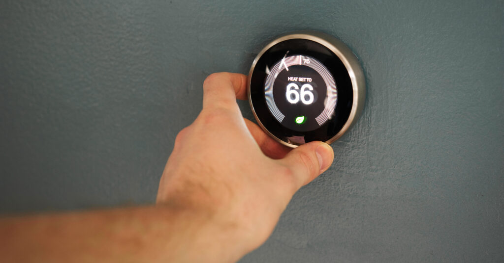 Hand adjusting temperature on electric thermostat