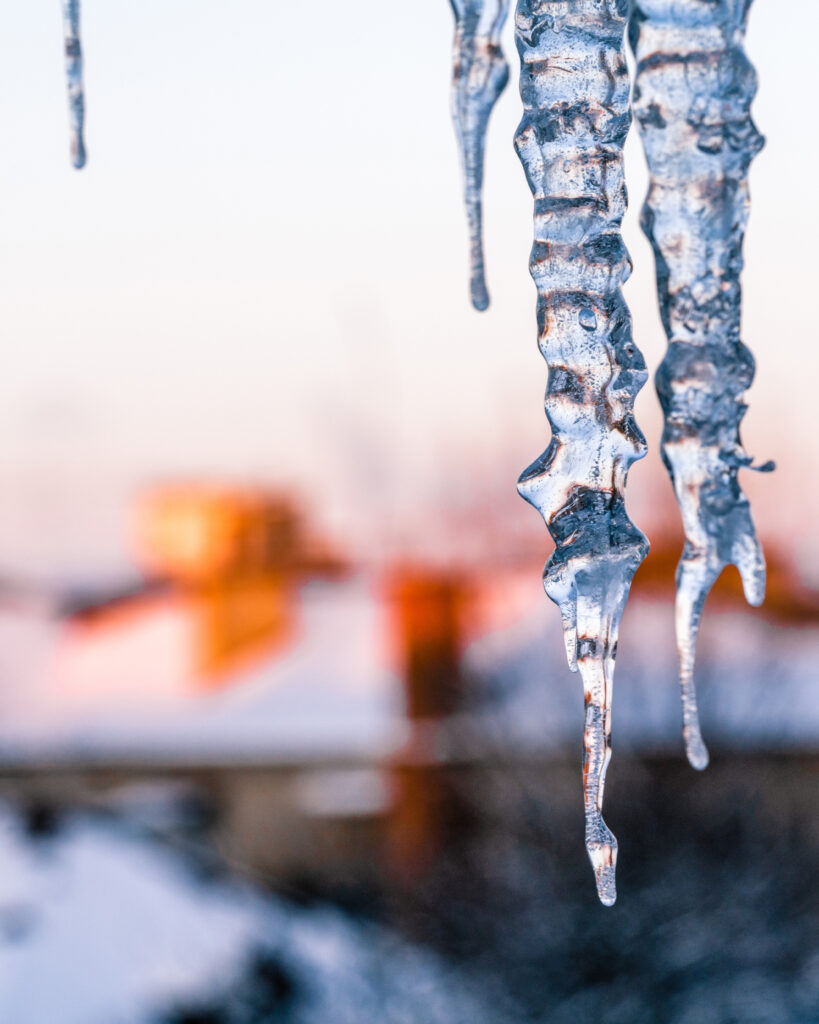 Background of bright transparent icicles against the backdrop of a snowy city