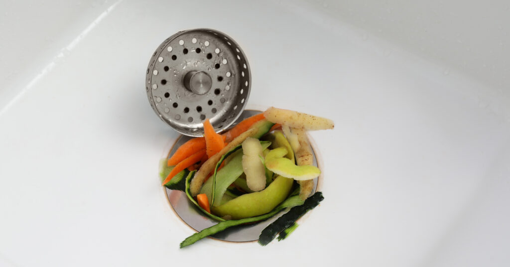 Vegetable scraps in kitchen sink with garbage disposal