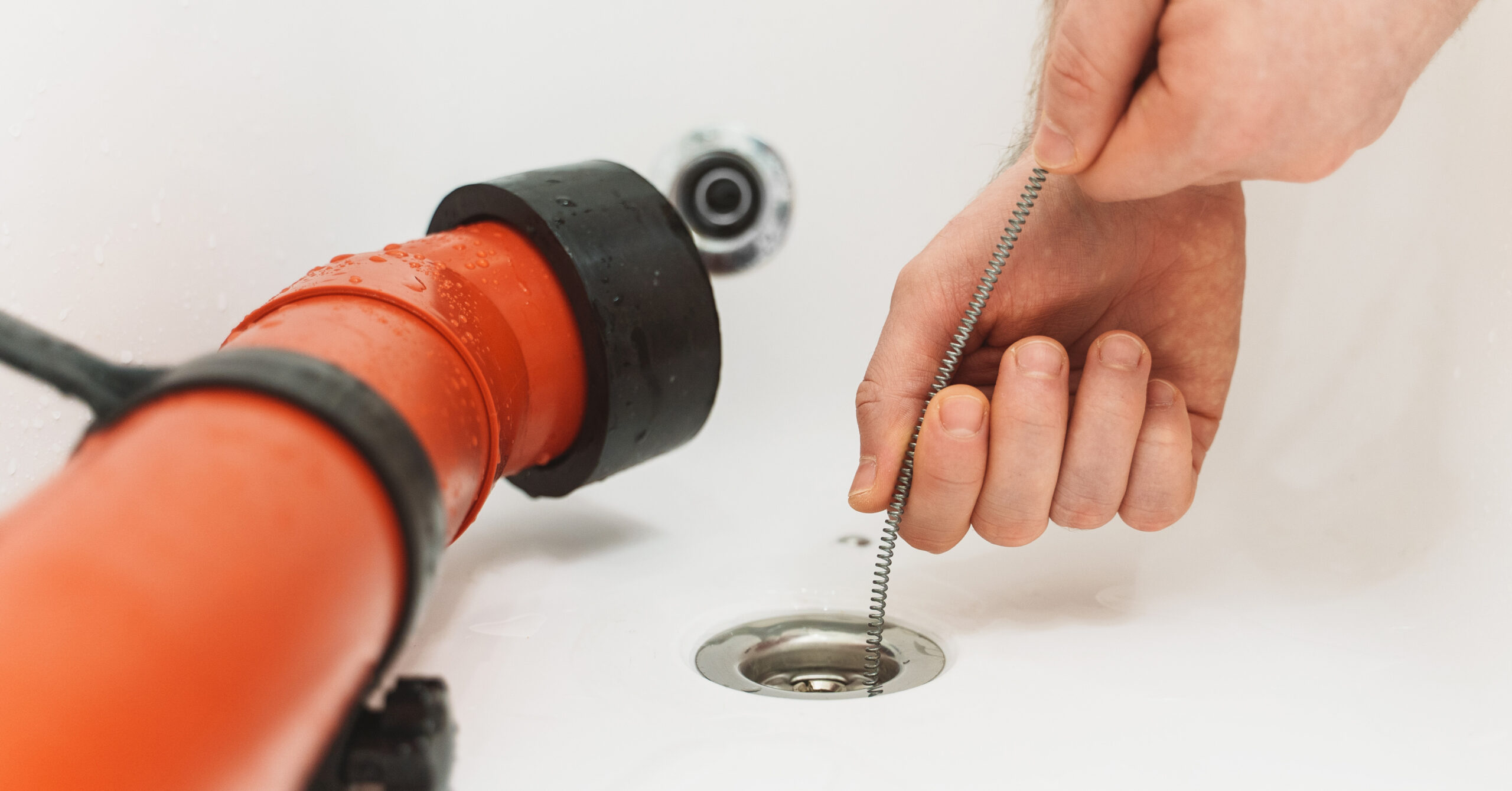A plumber puts a drain snake in a bathtub. Plumbers can provide drain cleaning tips to New York homeowners to avoid bad smells.