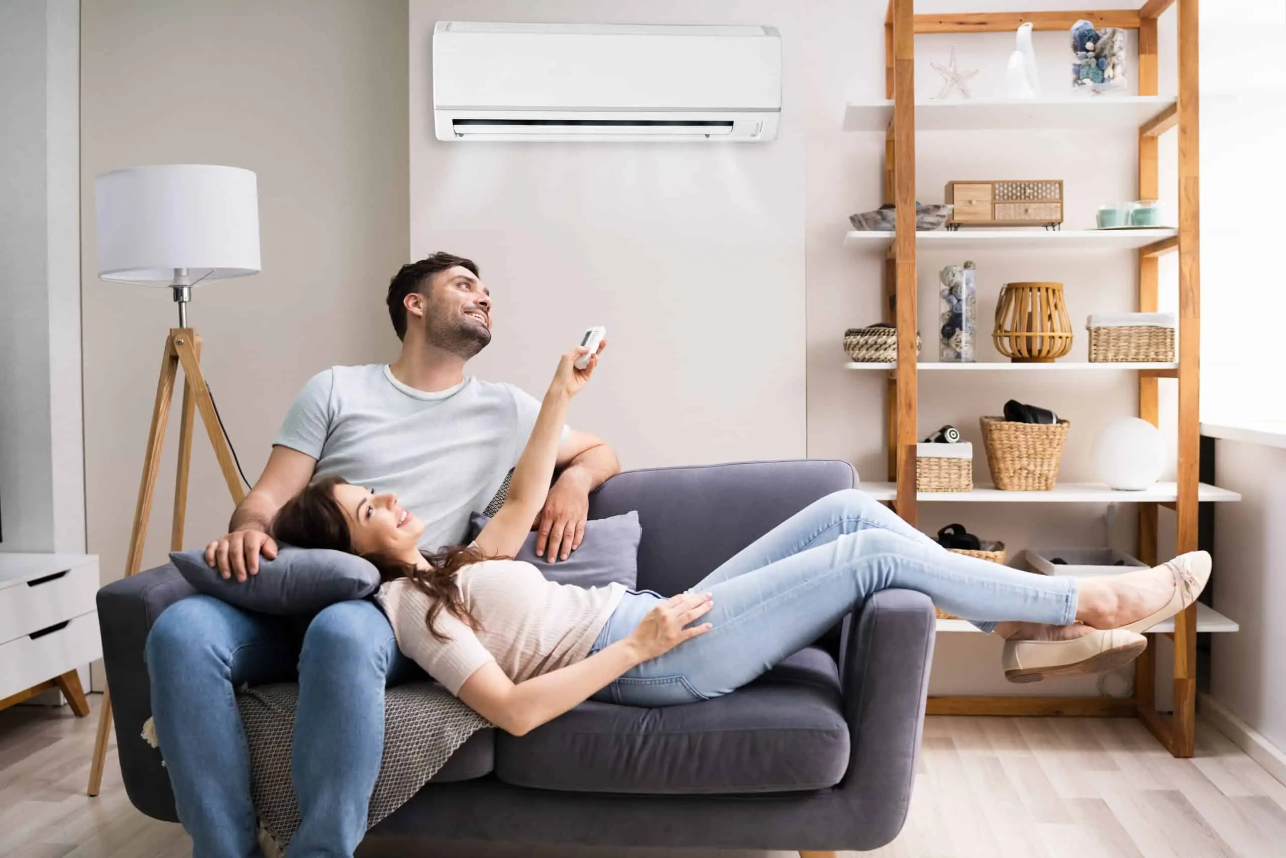 A couple relaxing on the couch under a ductless air conditioner