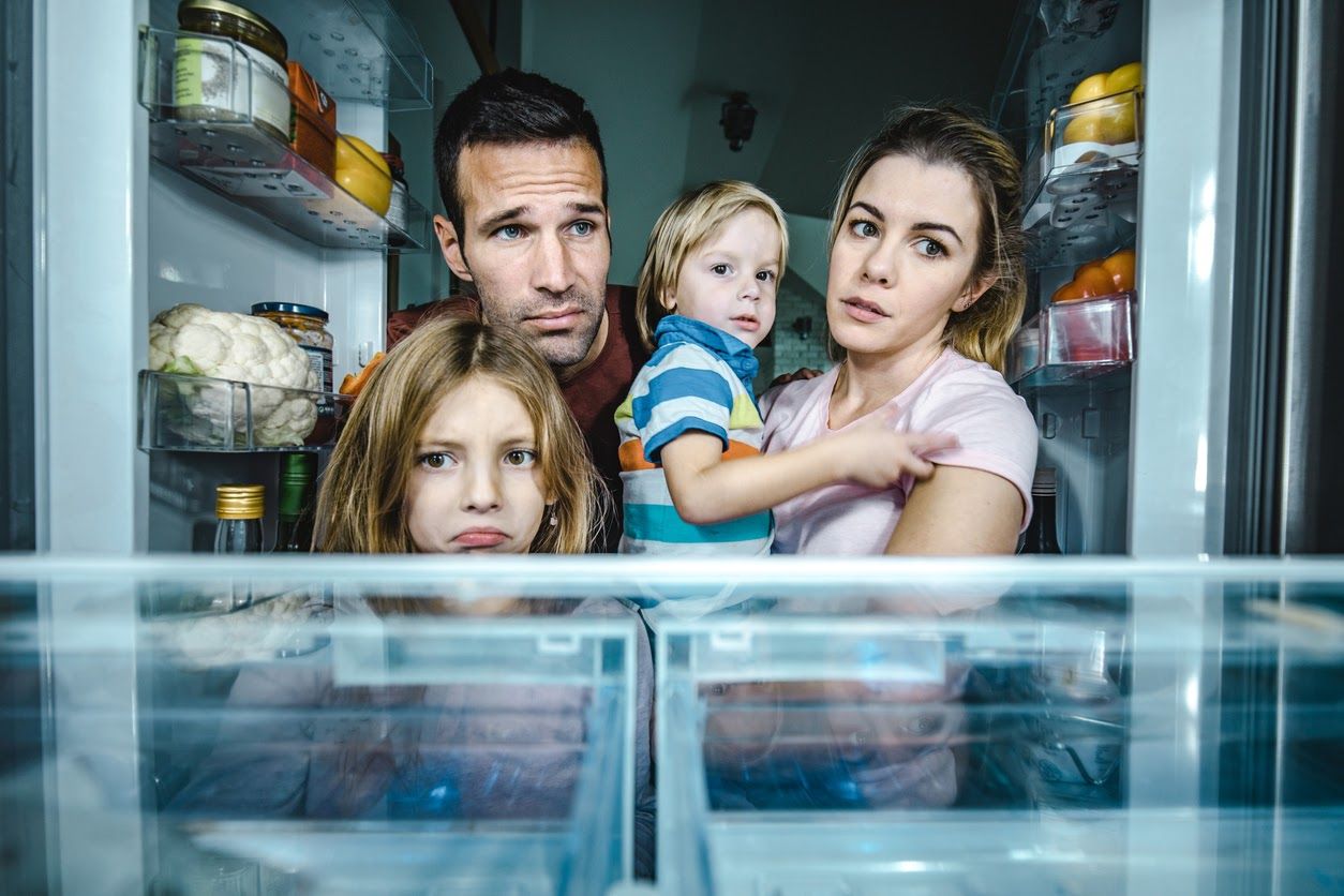 Family looking at empty refrigerator