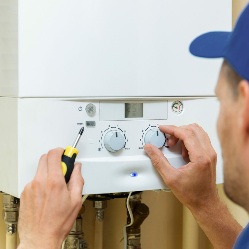 worker set up central gas heating boiler at home