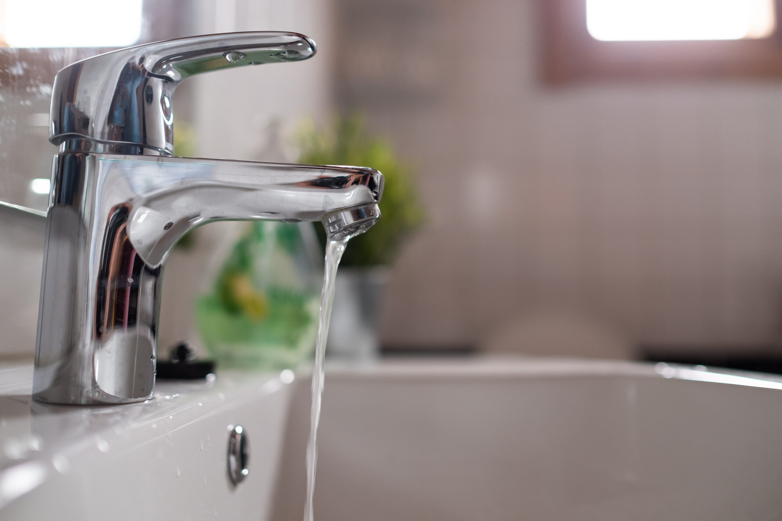 Faucet over sink with water flowing out of it.
