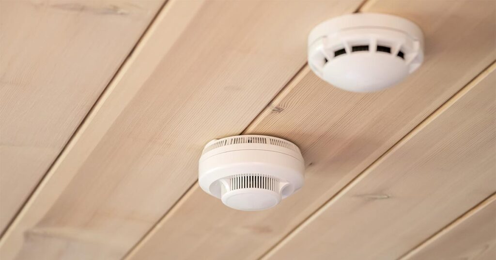 Hand installing smoke detector on ceiling