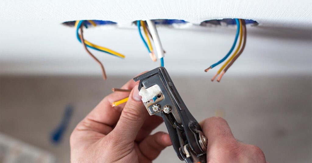 Electrician repairing electrical sockets by removing insulation from wires.