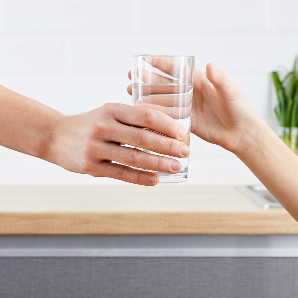 woman's hand gives glass of purified water to her child. Concept purification of water by Osmosis filter