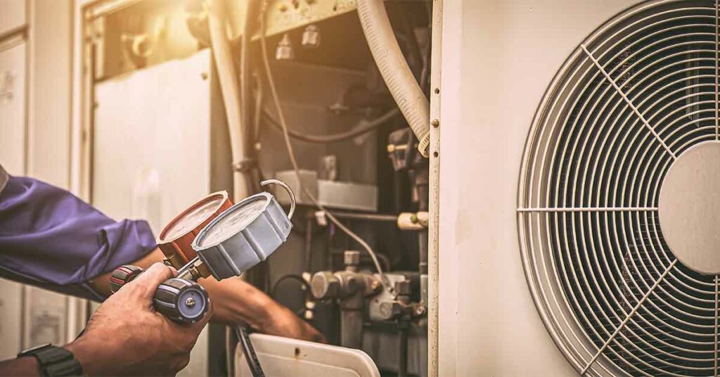 Heat and Air Conditioning, HVAC system service technician using measuring manifold gauge checking refrigerant and filling industrial air conditioner after duct cleaning maintenance outdoor compressor.