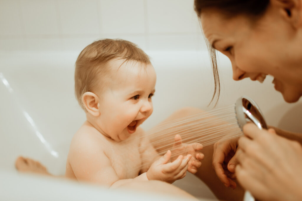 Mother bathing baby in the bathtub and laughing