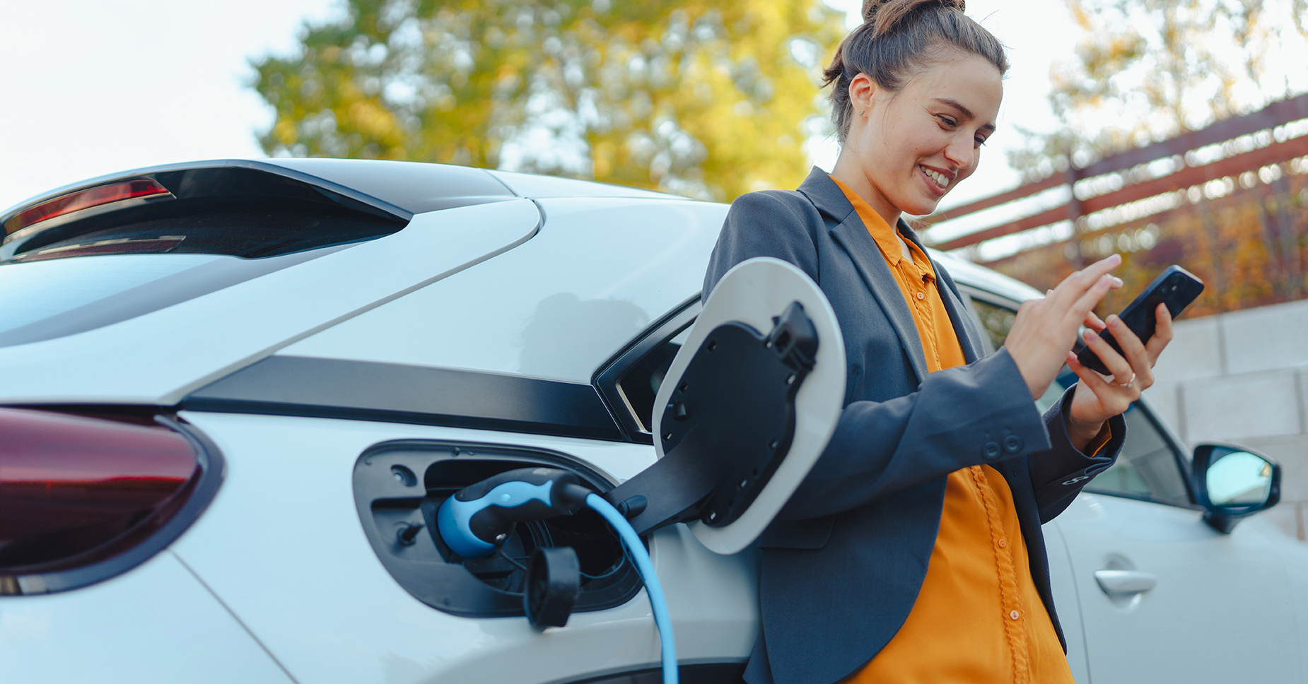 Woman leaving against her car while it's charging