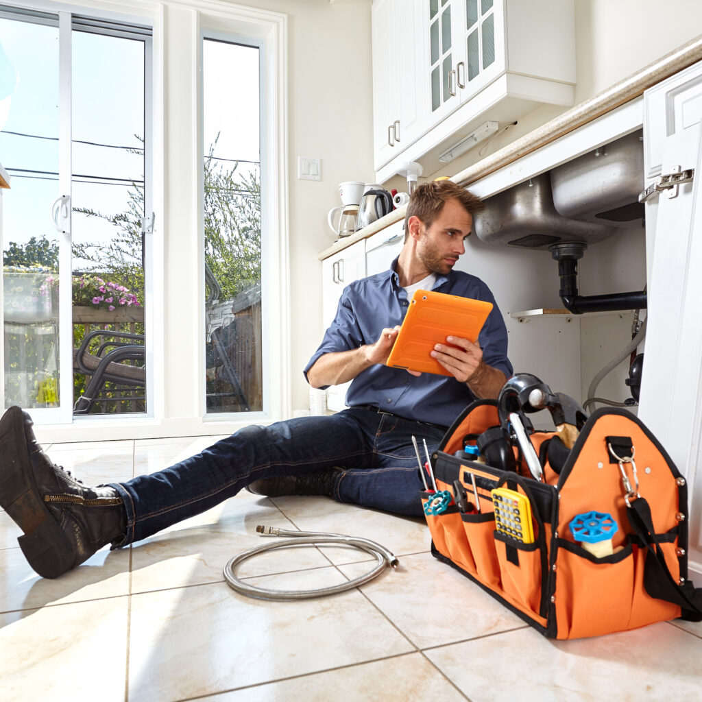 Plumber with tools doing reparation in the kitchen.