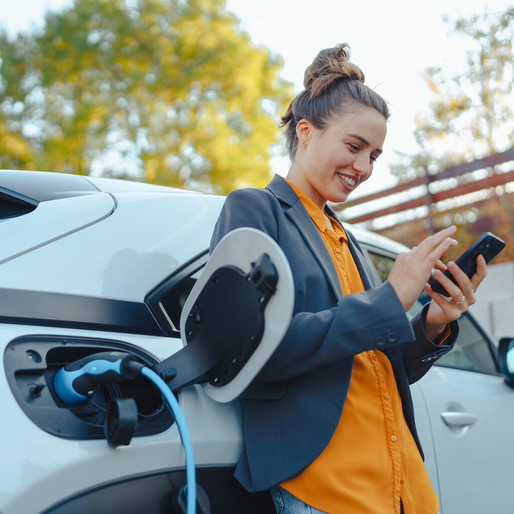 Woman leaving against her car while it's charging