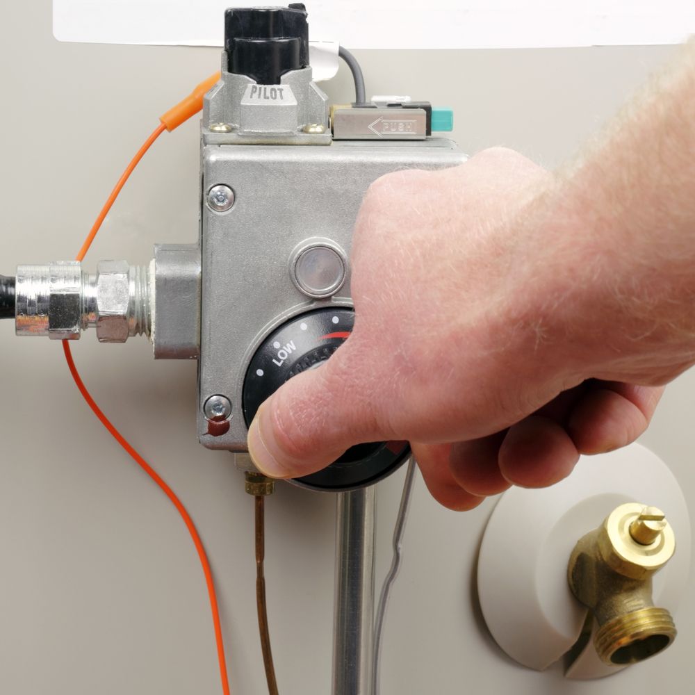 Hand turns knob to change temperature on water heater